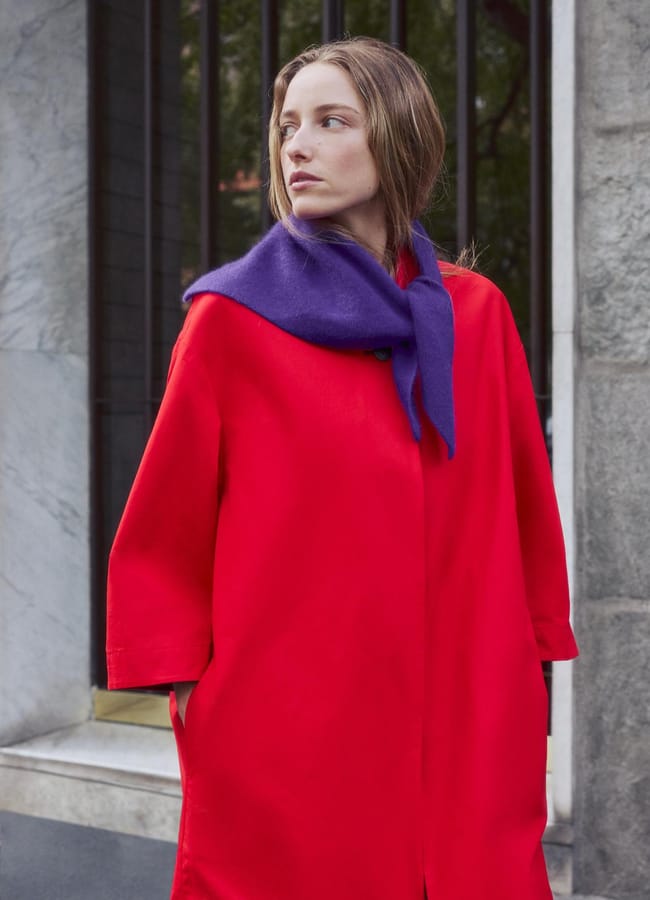 A person wearing a bright red coat and a purple scarf.