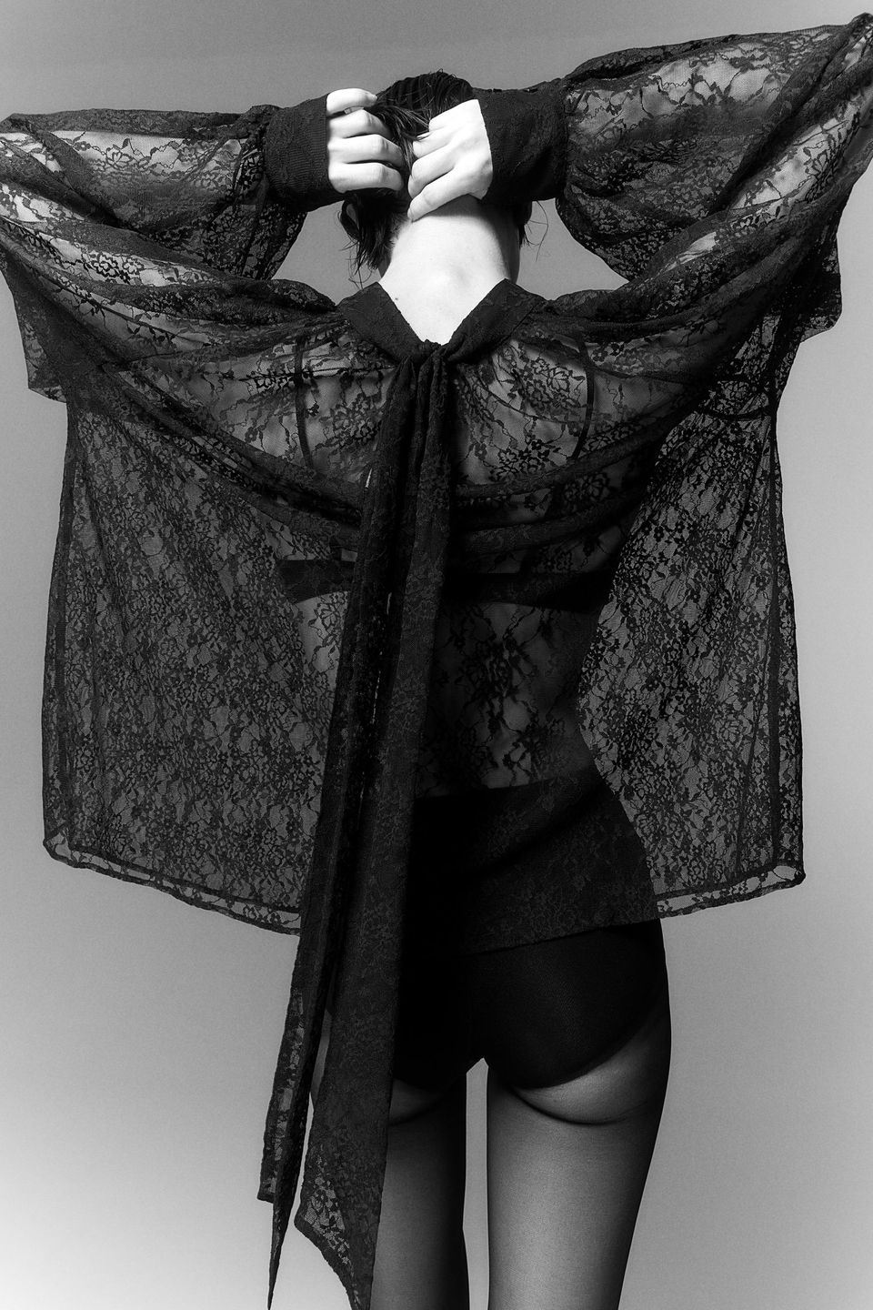 model from back in black lace blouse