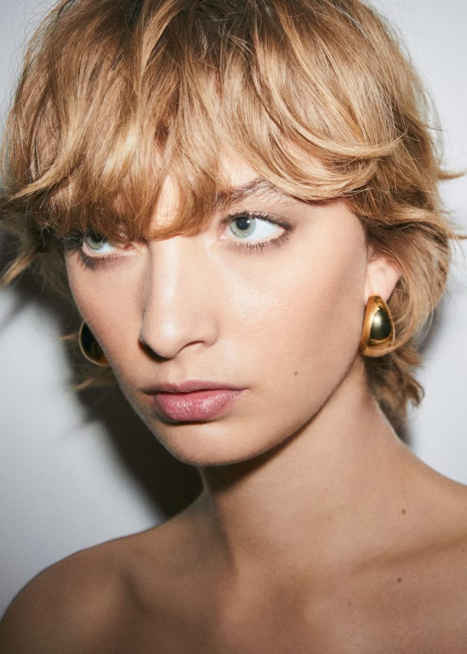 model wears gold volume hoop earrings