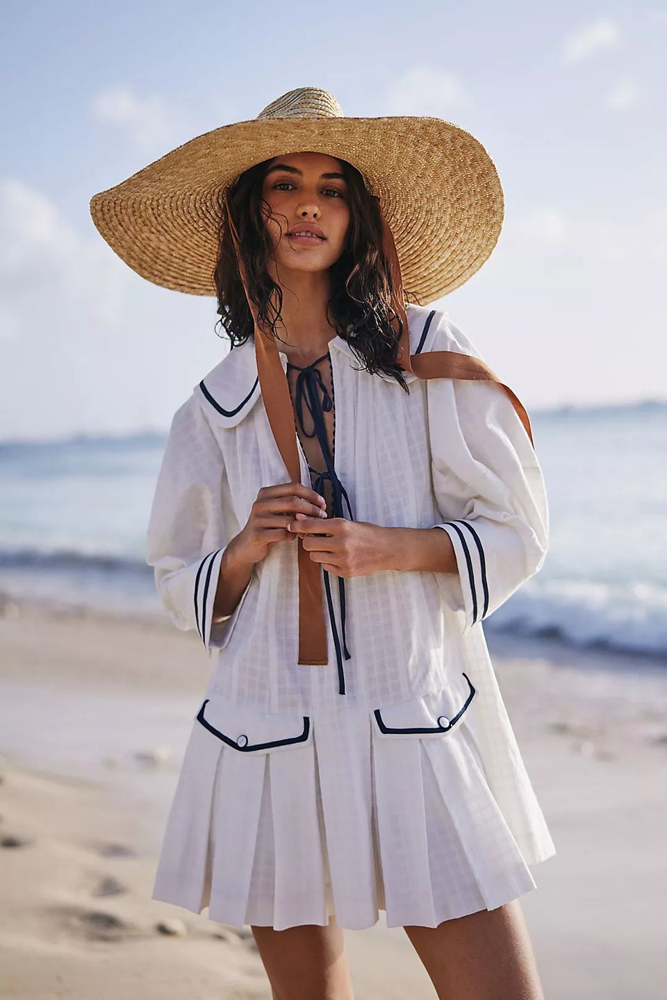 model on beach wearing white sailor dress and hat